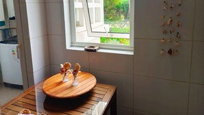 Una cucina con una finestra, un tavolo rotondo in legno e due vasi, più un elemento decorativo appeso al muro.