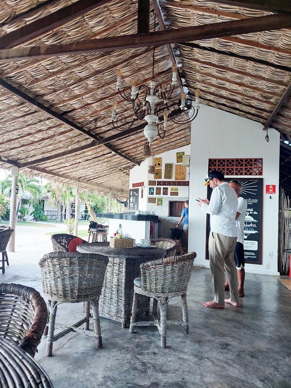 Un espace extérieur aménagé avec des meubles en osier, un bar et un toit de chaume.