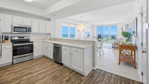 A modern kitchen with white cabinetry, stainless steel appliances, and a view to the outside. - Inn At Summerwind 501 - This Is It (Navarre)
