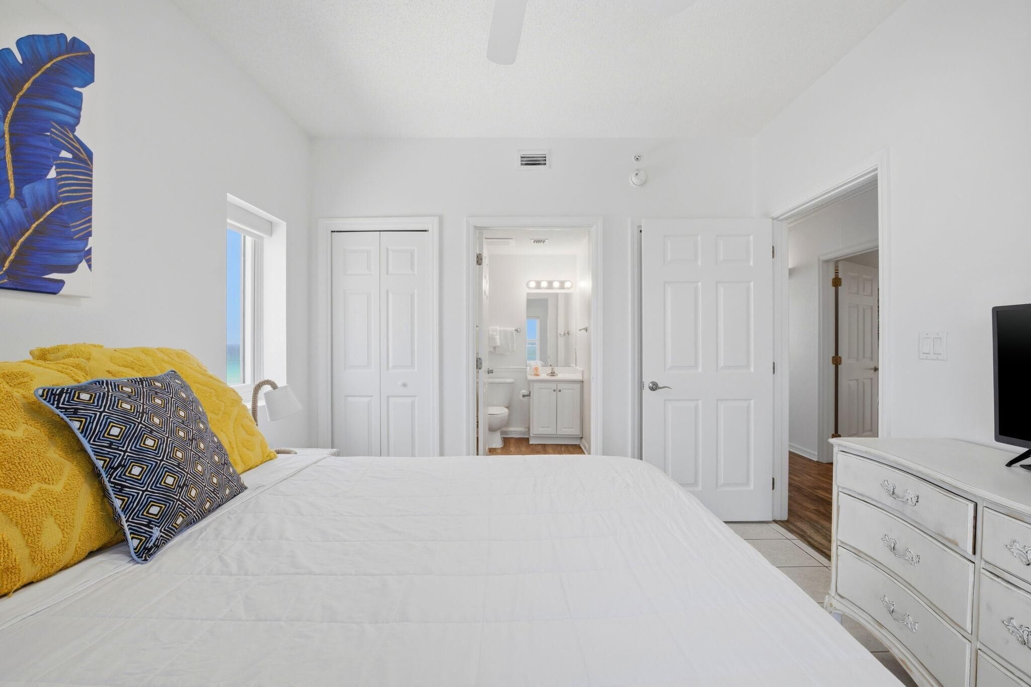 A bedroom with a bed, a dresser, and a television.