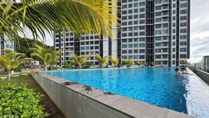A swimming pool surrounded by greenery and tall buildings. - JQ#11 City View Slide LoftBed 2R1B 5Pax Near Suria Mall, Gaya St, Sicc (Kota Kinabalu)