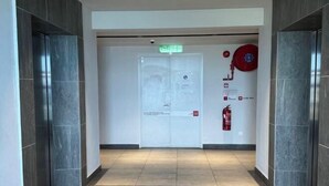 A hallway with a fire extinguisher and an emergency exit sign. - JQ#11 City View Slide LoftBed 2R1B 5Pax Near Suria Mall, Gaya St, Sicc (Kota Kinabalu)