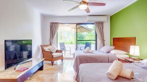 Camera d'albergo con televisione a schermo piatto, due letti, ventilatore a soffitto e vista sul verde.