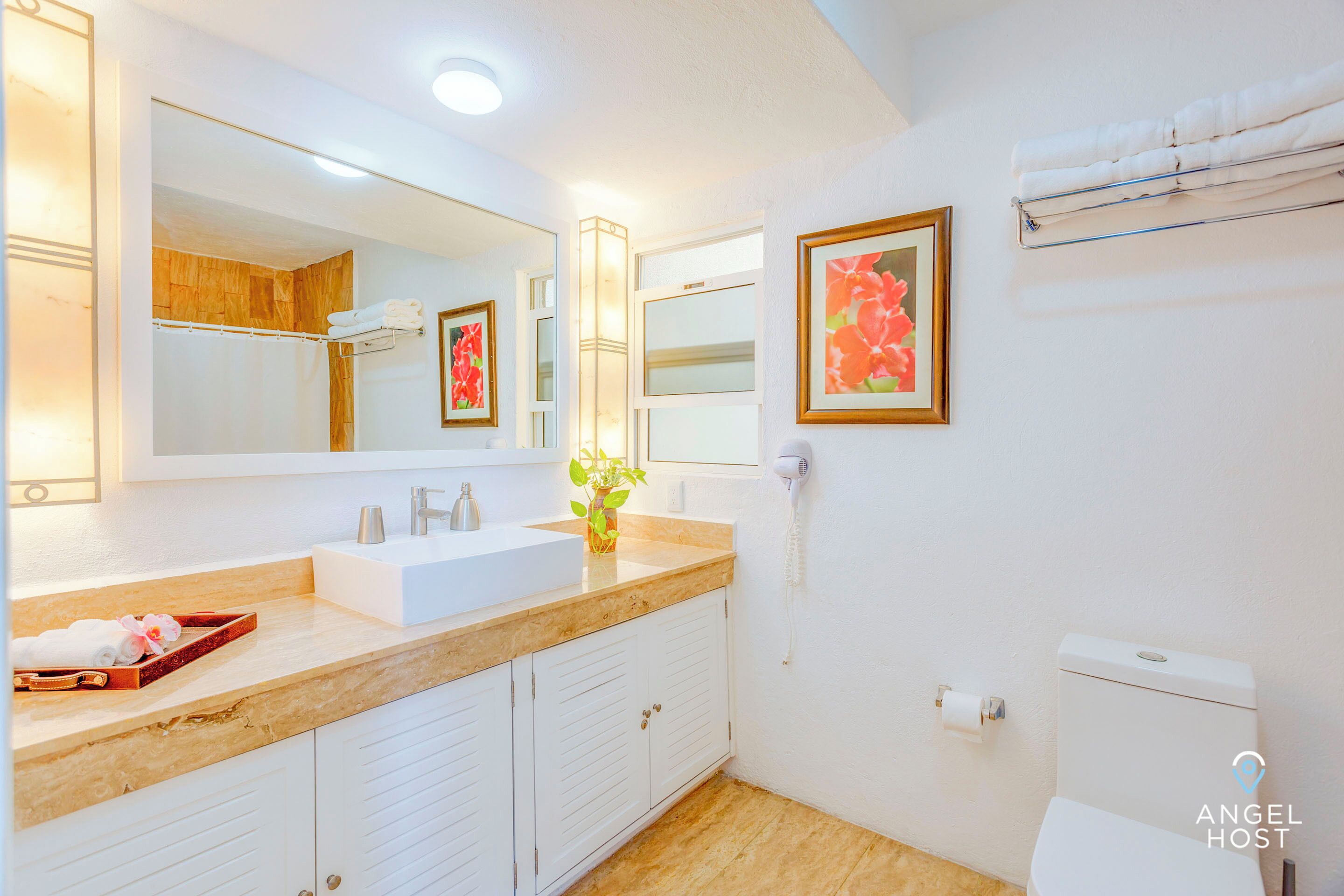 A bathroom with a white sink, a mirror, a toilet, and a towel rack.
