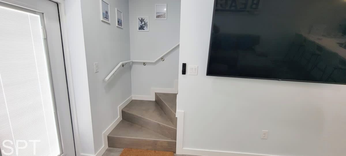 Una escala amb barana, una porta i una paret amb un gran finestral.