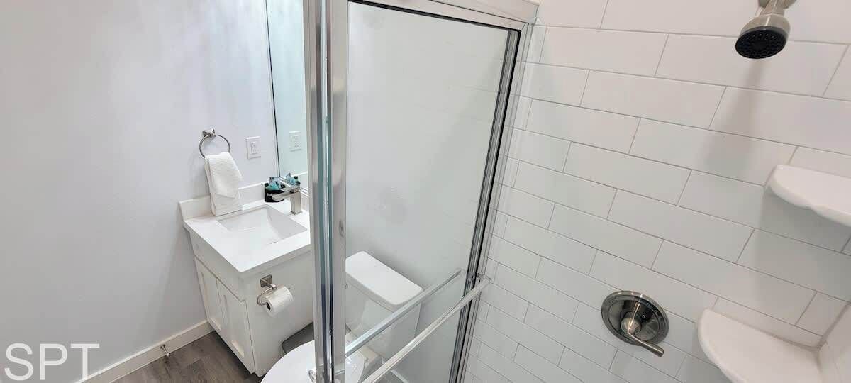A bathroom with a glass-enclosed shower, a white sink, and a toilet.