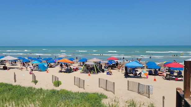 Une plage avec de nombreux parasols et des chaises de plage, ce qui indique qu’il s’agit d’une plage publique.