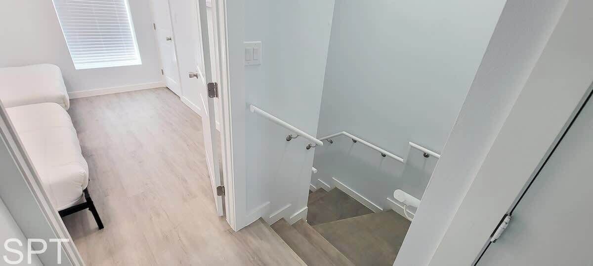 A staircase with handrails, a door, and a light switch.