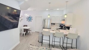 Une cuisine moderne dotée d’un grand îlot central, de meubles blancs et d’un éclairage suspendu.