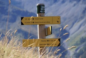 A directional signpost with multiple arrows pointing towards different destinations, including distances and directions. - CASA-Mezan, appartement cosy 2 chambres (Aiguilles)