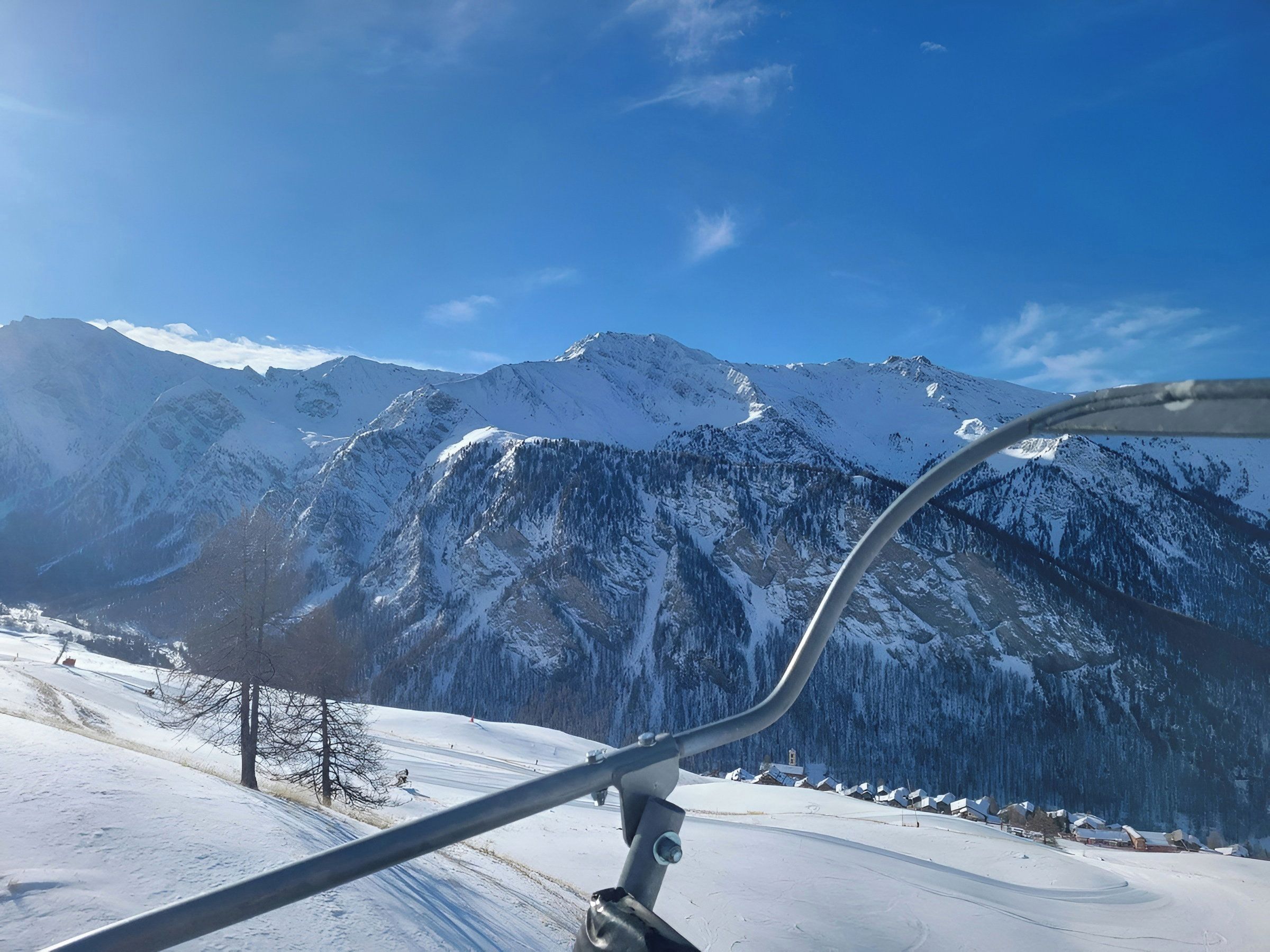 A snow-covered mountain landscape with a ski lift in the foreground.