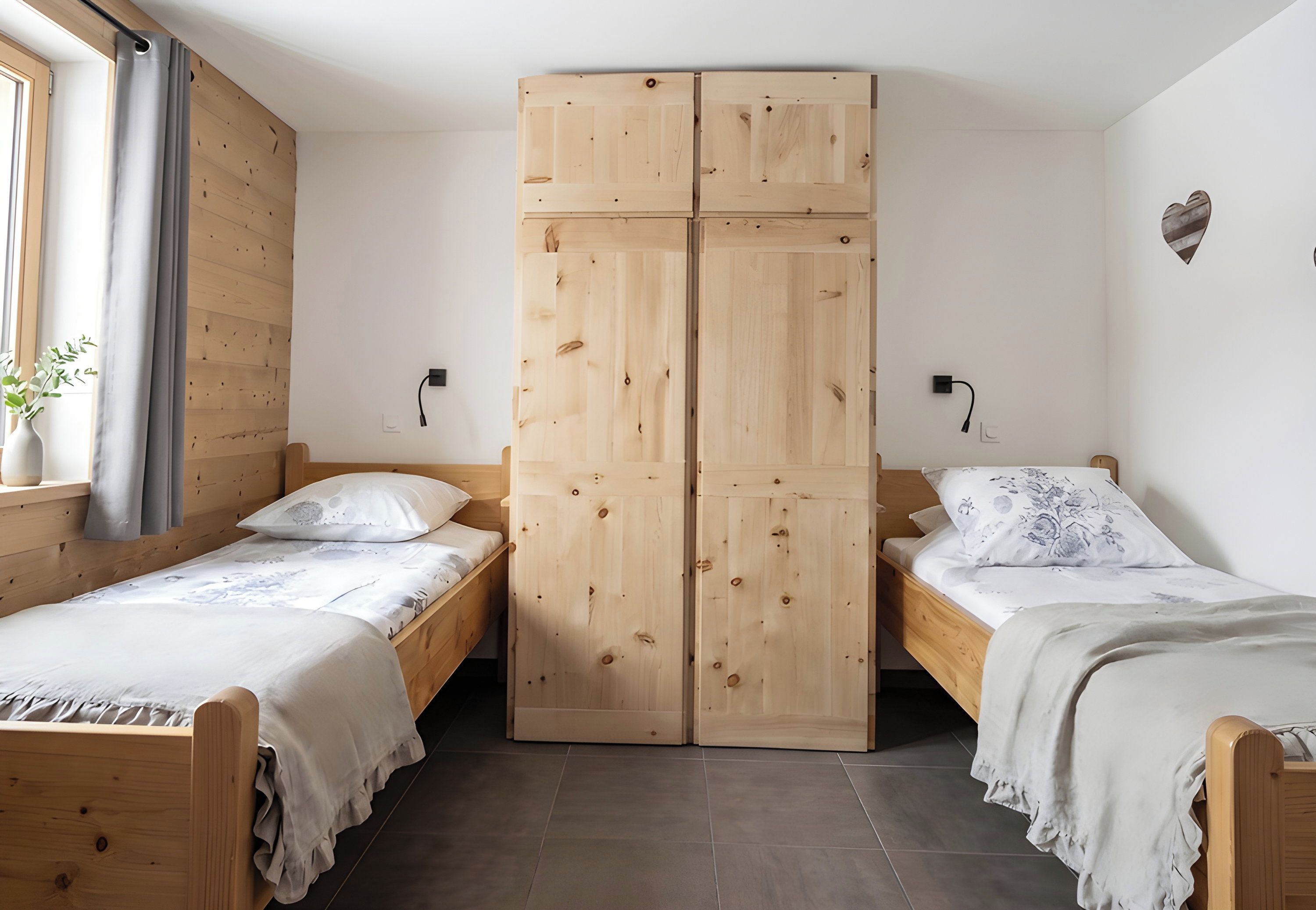 A room with two wooden beds, a wardrobe, and a window with curtains.