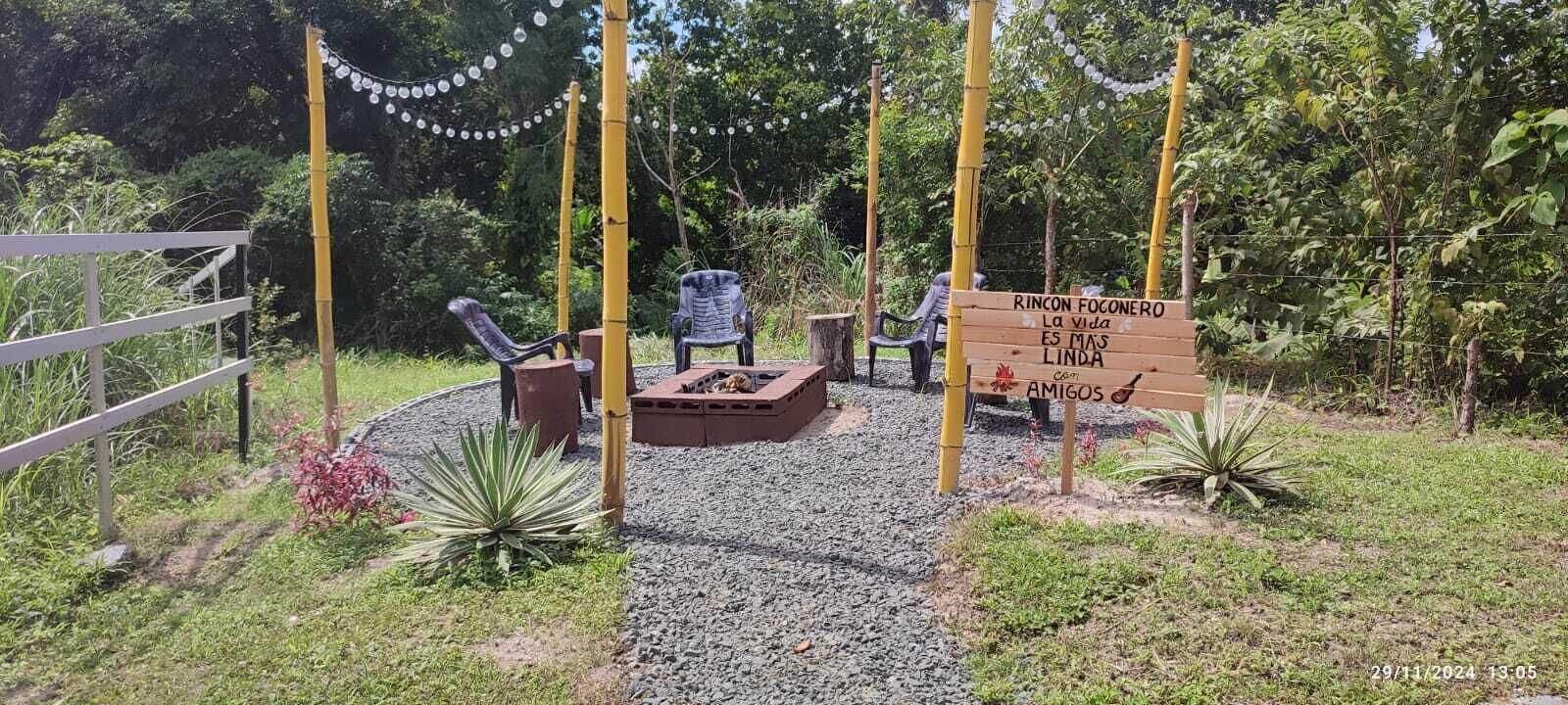 A garden area with a wooden sign, outdoor seating, and decorative lights.