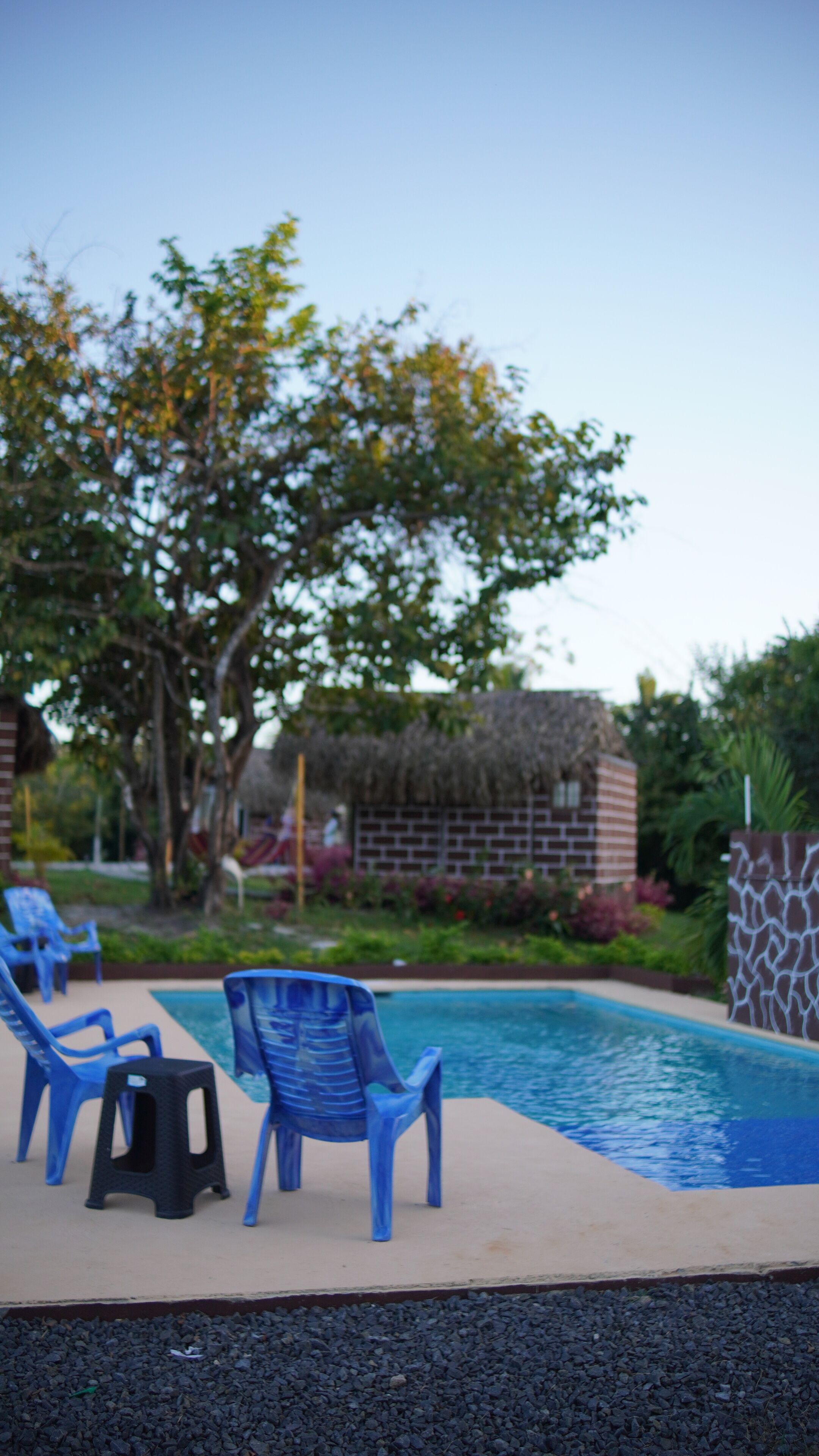 Un'area piscina con sedie di plastica blu e uno sgabello nero.