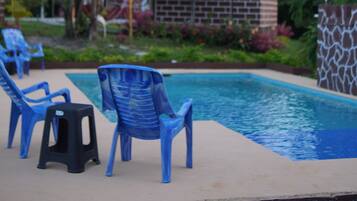 Un'area piscina con sedie di plastica blu e uno sgabello nero.