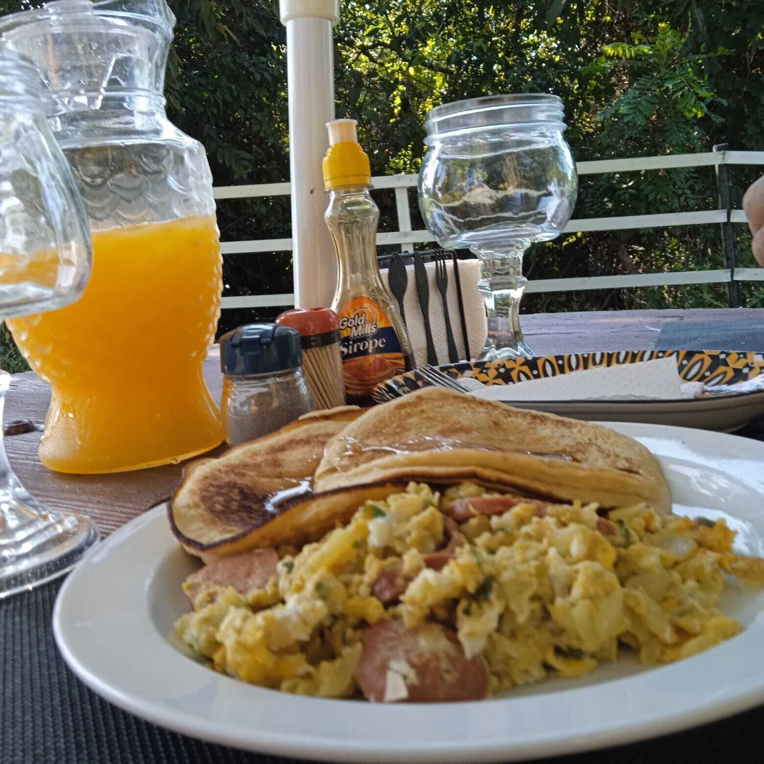 A breakfast setting with toast, scrambled eggs, and orange juice on a table.