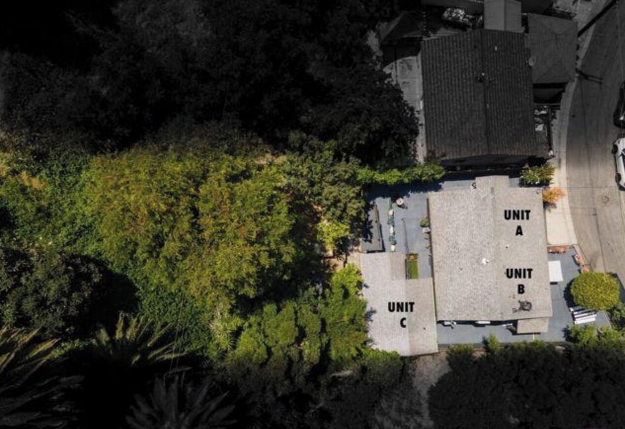 Vista aérea de un edificio con tres unidades identificadas (A, B, C) y abundante vegetación circundante.