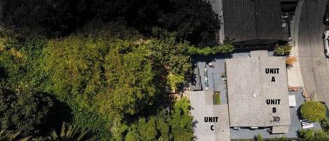 Vista aérea de un edificio con tres unidades identificadas (A, B, C) y abundante vegetación circundante.