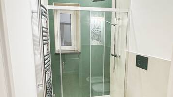 A modern bathroom with a glass-enclosed shower, a white toilet, and a bidet.