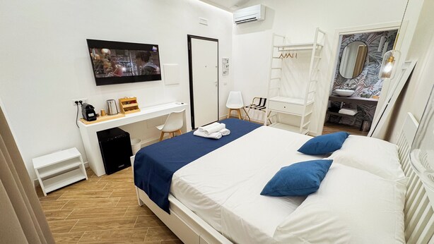 Habitación de hotel con cama, escritorio, silla, televisor, armario y baño.