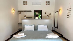 A neatly made bed with two pillows and a folded towel, a bedside table, a mirror, wall-mounted lights, and a small shelf with decorative items. - Room-luxurious Lodge Room 2 (Beberibe)