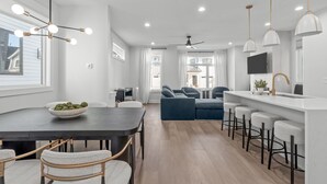 A modern kitchen with a dark countertop, white chairs, and a bowl of fruit. - Spacious 4 Bedroom House in Charming Downtown Raleigh with Amazing Views! (Raleigh)