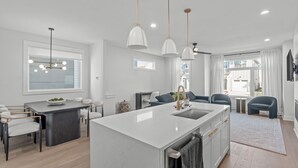 A modern kitchen with a central island, pendant lighting, and a view of the city. - Spacious 4 Bedroom House in Charming Downtown Raleigh with Amazing Views! (Raleigh)