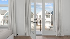 A bedroom with a large sliding glass door leading to a balcony. - Spacious 4 Bedroom House in Charming Downtown Raleigh with Amazing Views! (Raleigh)