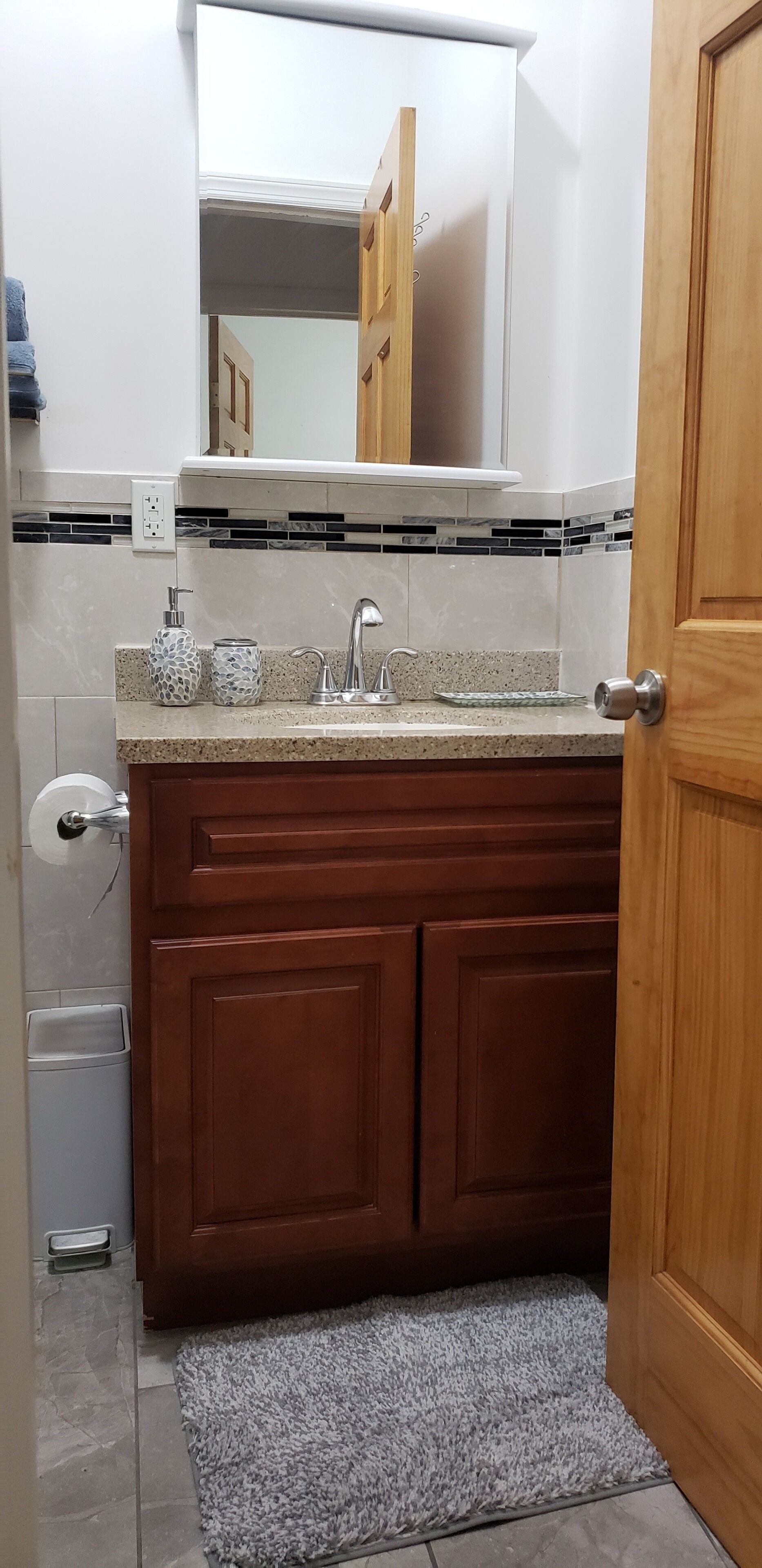 A bathroom with a sink, mirror, and wooden cabinets.