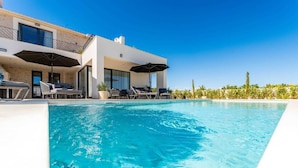 A modern poolside area with a clear blue pool, lounge chairs, and umbrellas. - Luxury Villa Waterlily with Pool (Vodice)