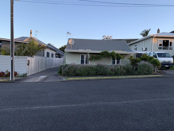 A residential house with a grey roof, satellite dish, and a white fence.