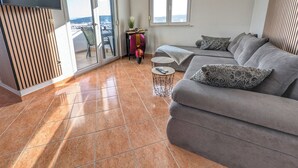 Un salon moderne avec un canapé gris, une petite table ronde et un téléviseur fixé au mur.