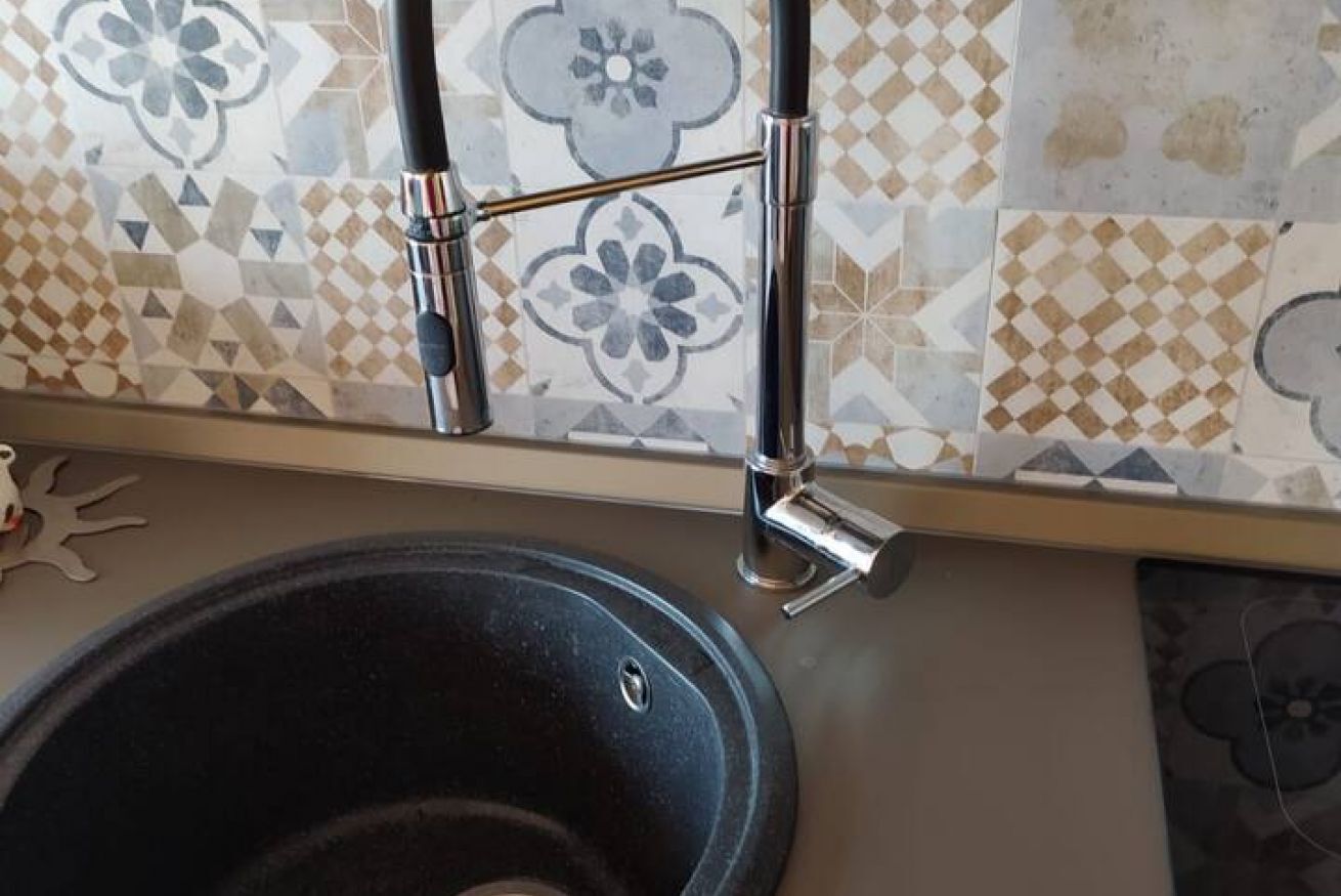 Un lavamanos de baño con un grifo moderno y un salpicadero decorativo de azulejos.