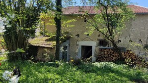 Ein rustikales Steinhaus mit rotem Ziegeldach, einer Holztür und einem kleinen Fenster.
