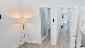 Un pasillo con una lámpara de pie, puertas blancas y una vista a otra habitación.