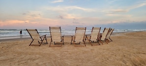 Una spiaggia con sei sdraio di legno disposte in fila.