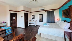 Une chambre d’hôtel avec un lit, des meubles en bois, un bureau et un ventilateur de plafond.