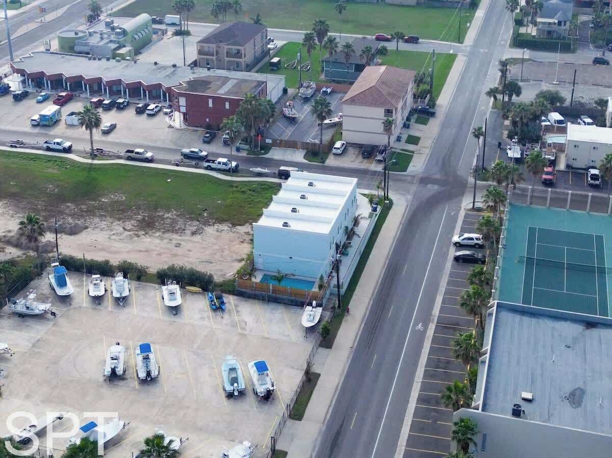 Une vue aérienne d’une zone côtière avec un grand bâtiment, des parkings et plusieurs bateaux.