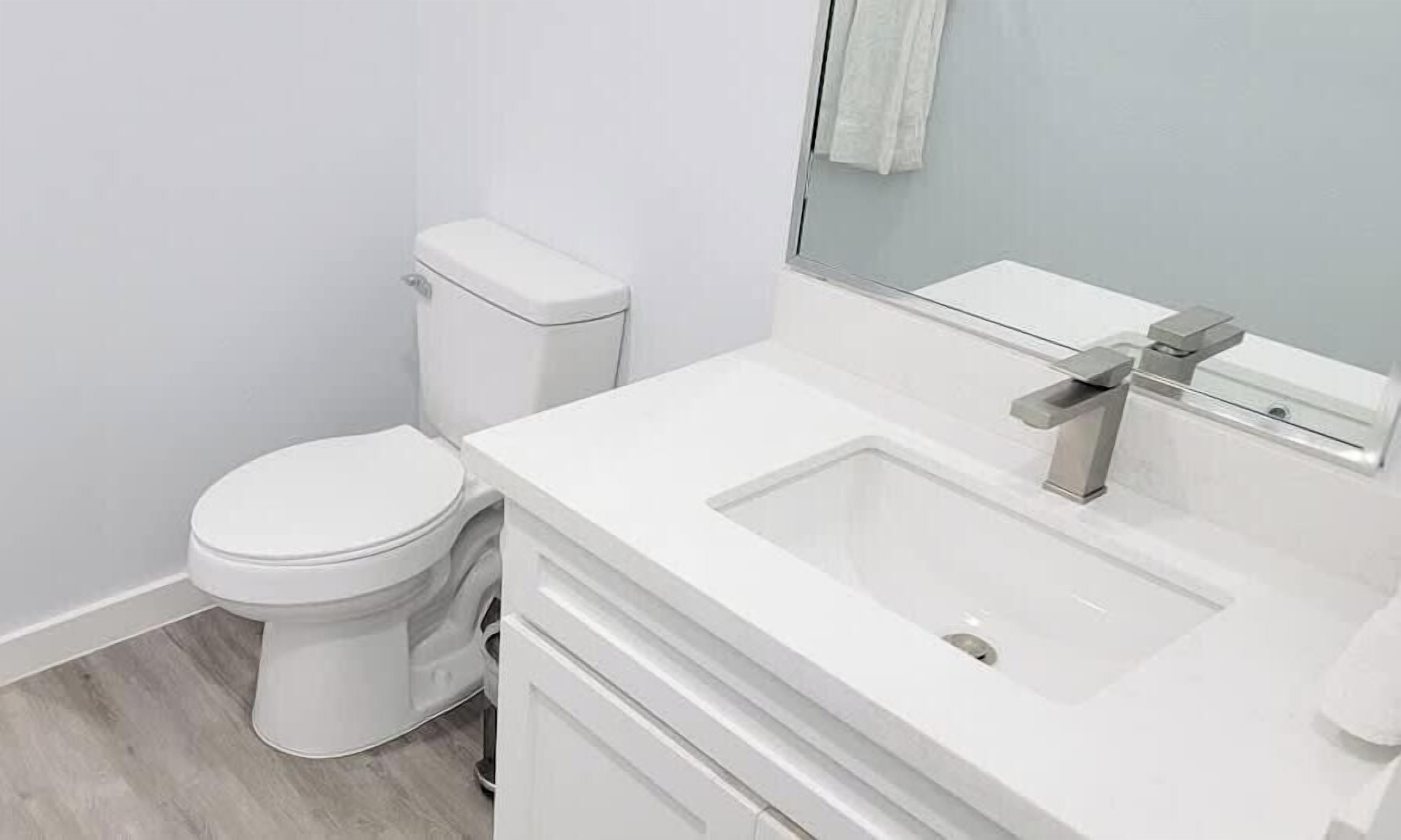 Een moderne badkamer met toilet, wastafel en spiegel.