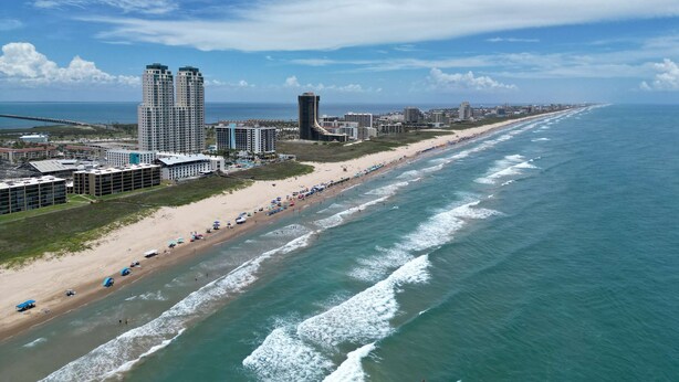 Eine Küstenstadt mit Strand, Hochhäusern und blauem Himmel.