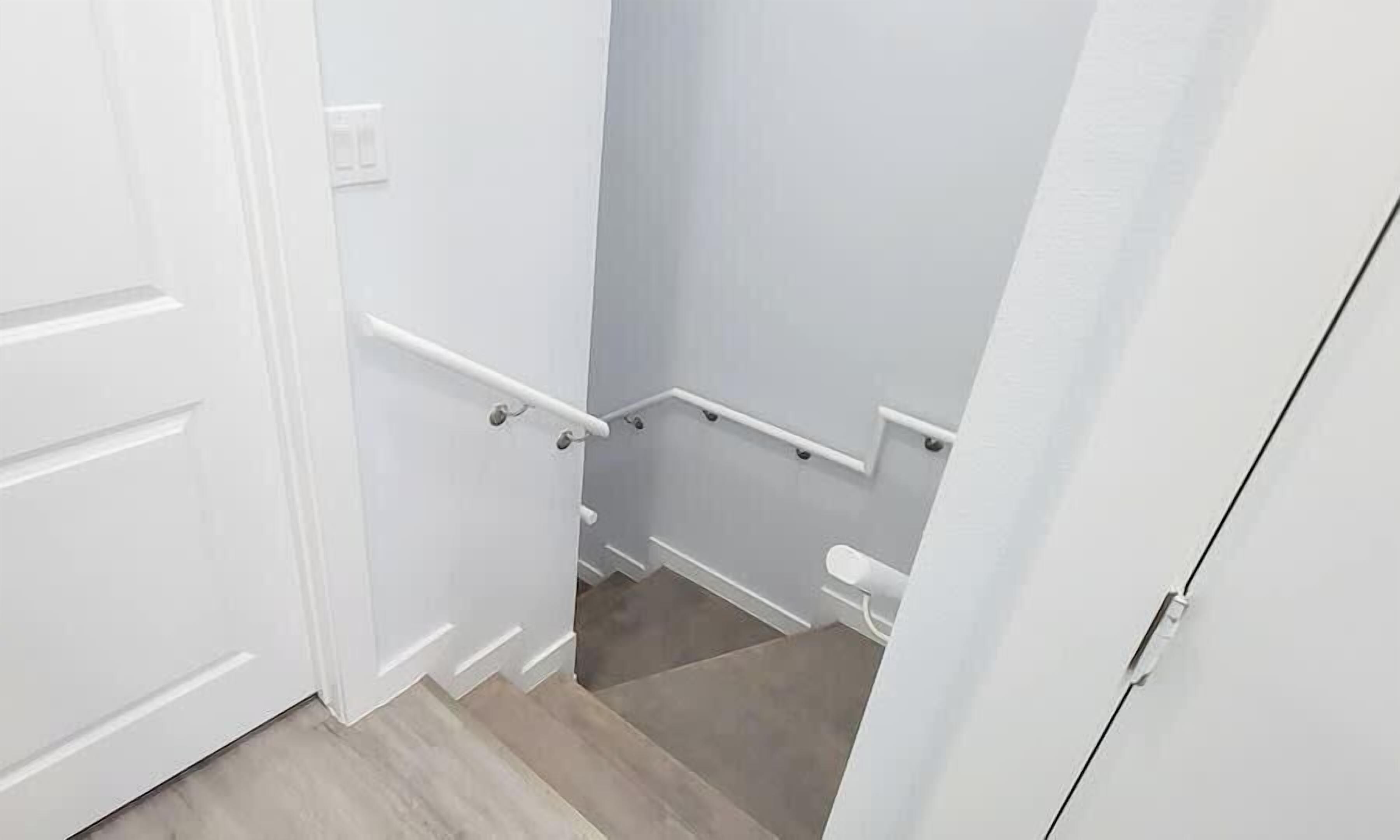 Una escalera estrecha con barandilla, una puerta a la izquierda y otra a la derecha.