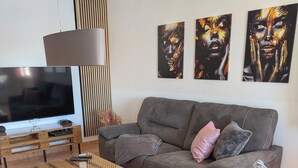 Ein modernes Wohnzimmer mit grauem Sofa, einem Holztisch und einem Flachbildfernseher.