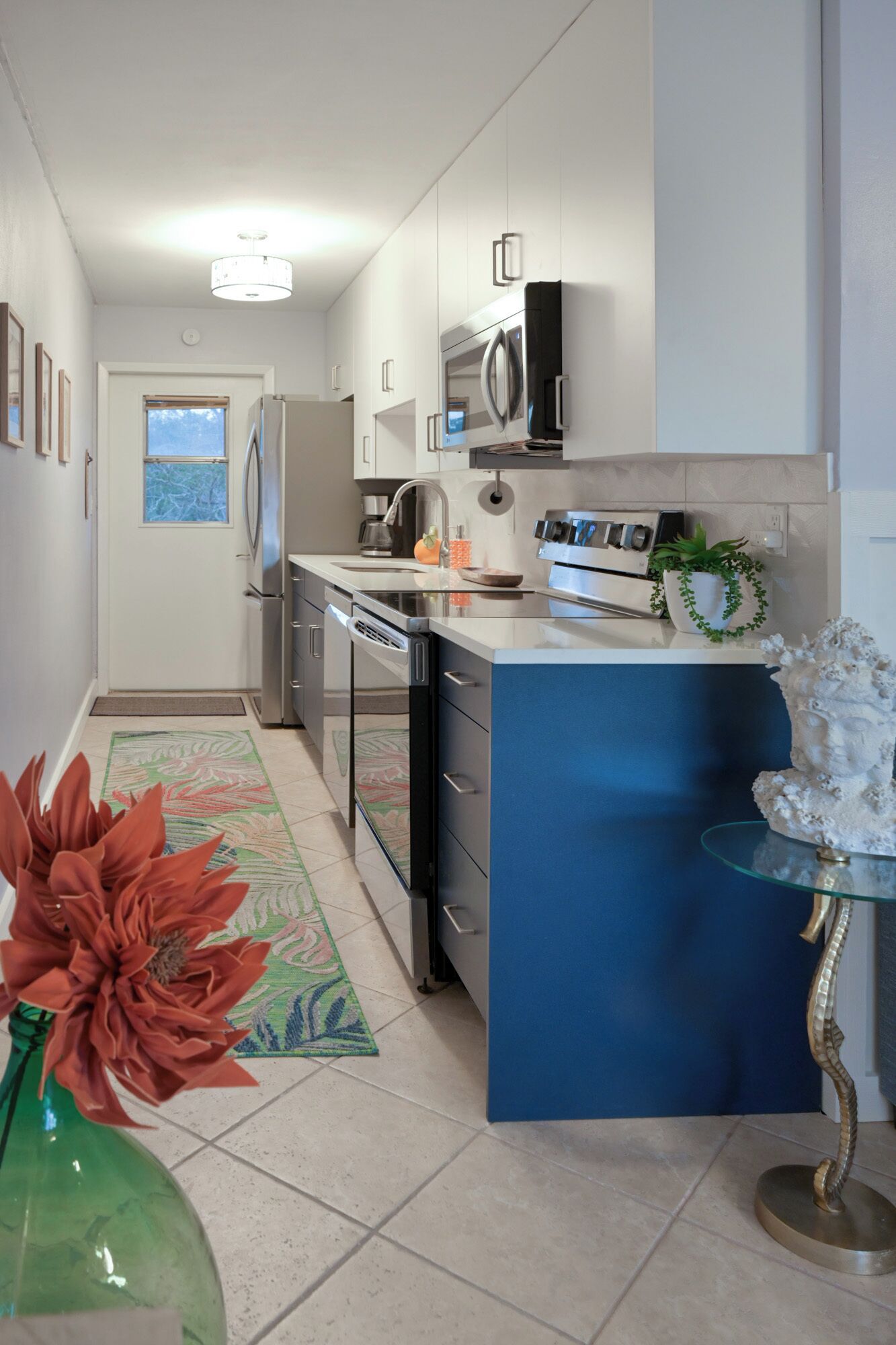 A modern kitchen with white cabinets, stainless steel appliances, and a blue island.