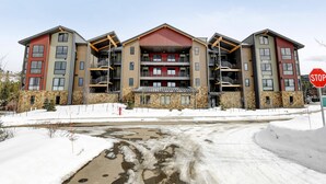 A multi-story building with a stone facade, balconies, and a red roof.