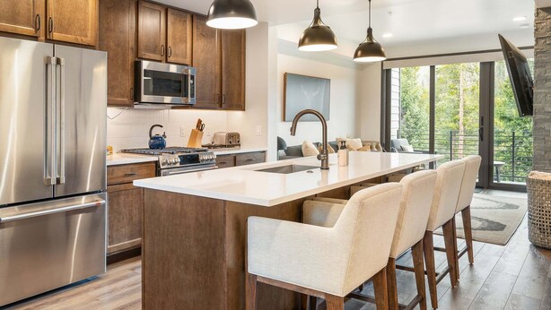 A modern kitchen with stainless steel appliances, wooden cabinets, and a large island with bar stools.
