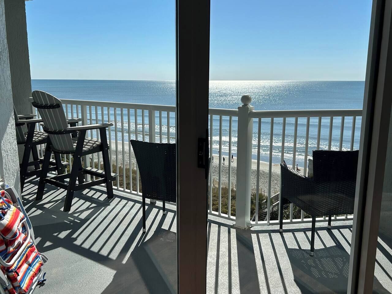 A balcony with a view of the ocean, featuring two chairs and a small table.