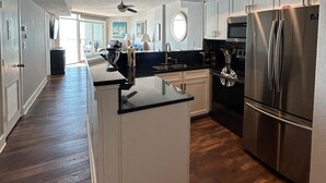 A modern kitchen with stainless steel appliances, a black countertop, and white cabinetry.