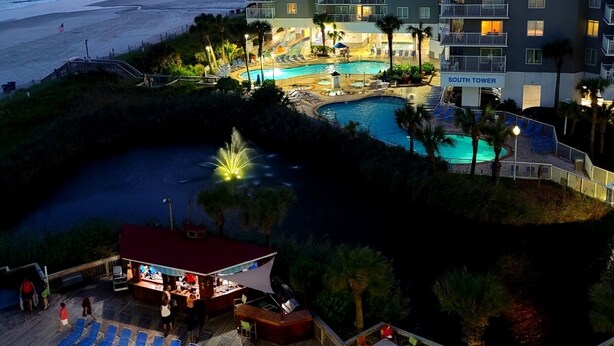 A hotel with a pool, beach view, and multiple balconies.