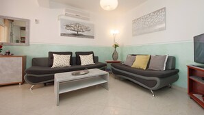 Una sala de estar moderna con dos sofás, una mesa de centro, un mueble para televisión y un cuadro en la pared.
