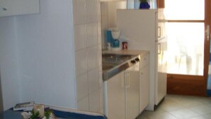 A compact kitchen with a stove, a coffee maker, and a small countertop.